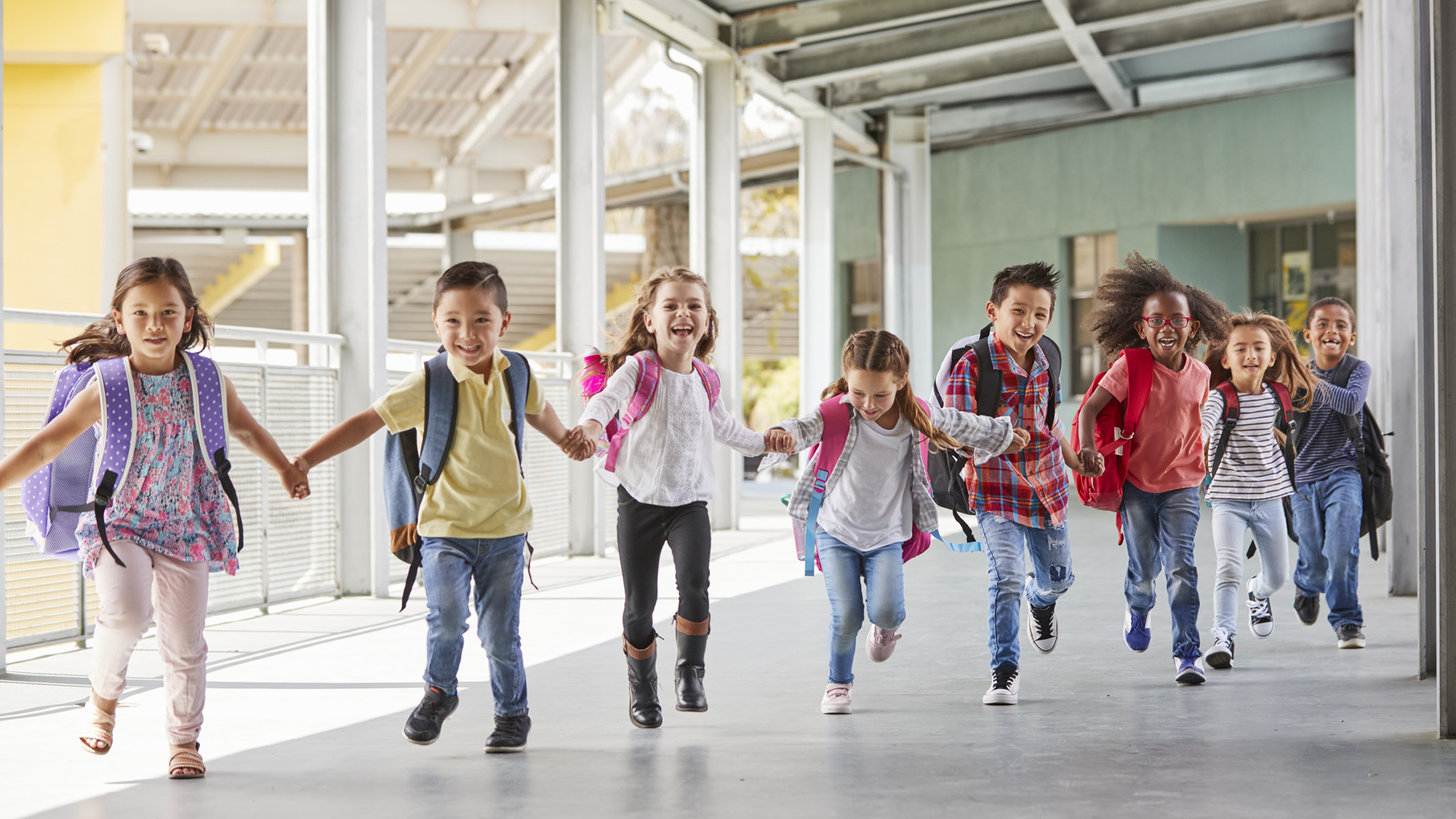 Children holding hands with backpacks