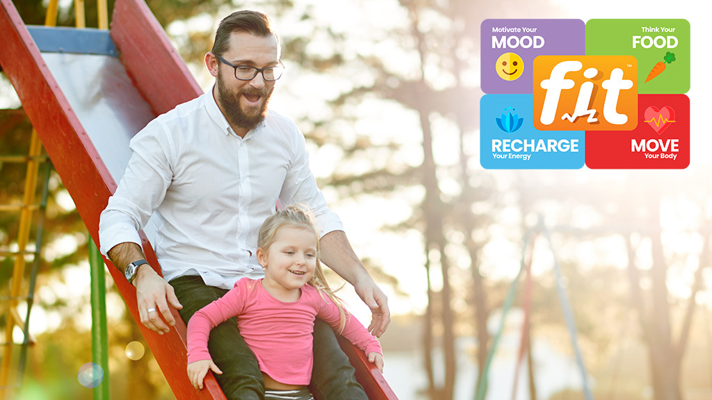 Father and daughter playing on a playground slide