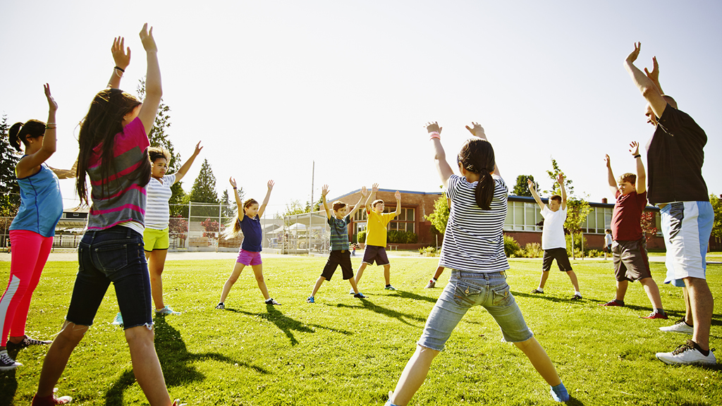Kids doing exercises on a grassy field outside