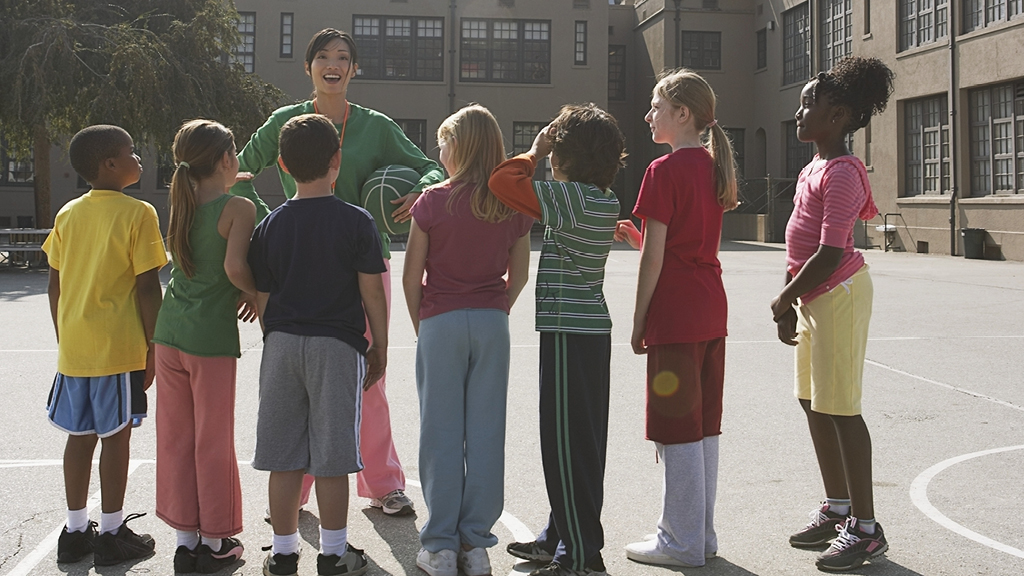 Adult leader explaining how to play a game to a group of kids