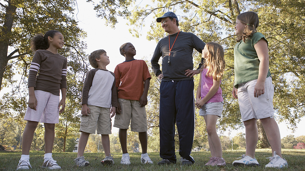 Adult leader helping kids learn game outside