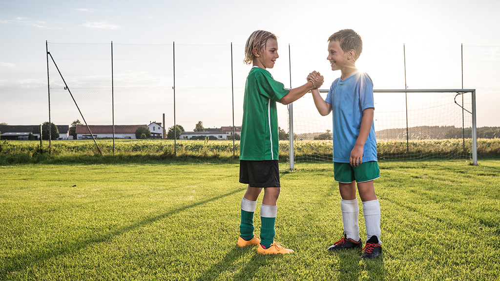 two children greeting each other on soccer field