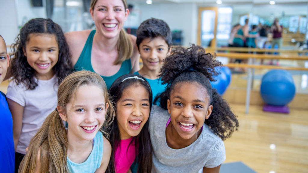Happy children with yoga instructor in studio - Sanford fit